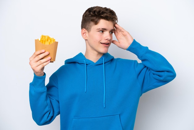 Adolescente ruso hombre sujetando patatas fritas aislado sobre fondo blanco sonriendo mucho