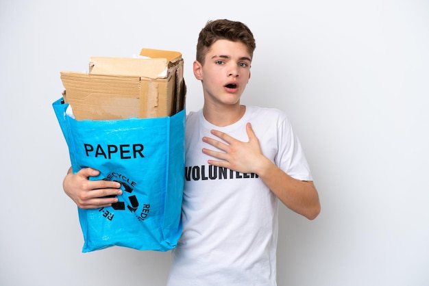 Adolescente ruso sosteniendo una bolsa de reciclaje llena de papel para reciclar aislado de fondo blanco sorprendido y conmocionado mientras miraba a la derecha