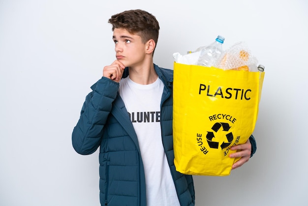 Adolescente russo segurando um saco cheio de garrafas plásticas para reciclar em fundo branco e olhando para cima