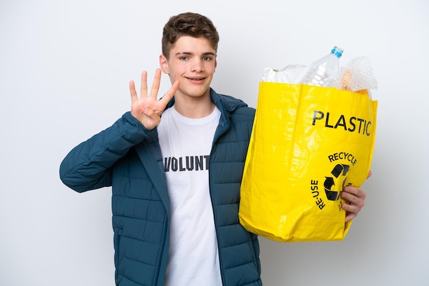 Adolescente russo segurando um saco cheio de garrafas plásticas para reciclar em fundo branco feliz e contando quatro com os dedos