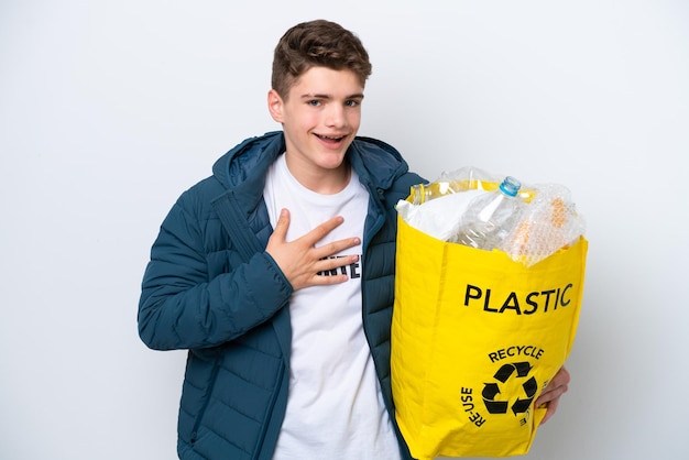 Adolescente russo segurando um saco cheio de garrafas plásticas para reciclar em fundo branco sorrindo muito