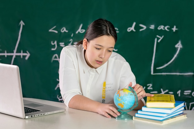 adolescente sentada à mesa e olhando para o conceito de aprendizagem on-line do globo