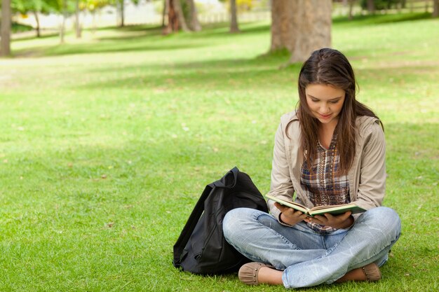 Adolescente sentado mientras lee su libro de texto