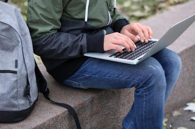 Adolescente sentado no parapeito com laptop no dia de outono close-up