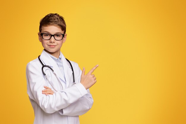 Adolescente sério em uniforme de médico apontando para o espaço vazio