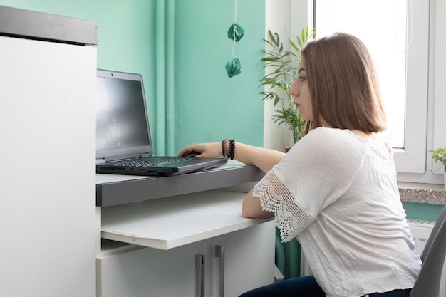 Un adolescente se sienta frente a una computadora portátil con la intención de aprender a vivir en línea