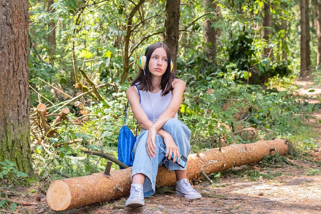 Un adolescente se sienta en el parque y escucha música con auriculares.