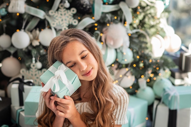 Adolescente soñadora feliz con caja de regalo de Navidad.