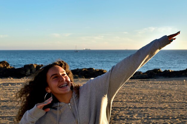 Foto una adolescente sonriente haciendo gestos mientras está de pie en la playa