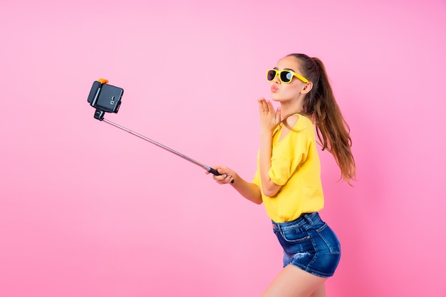 Adolescente sonriente haciendo selfie con palo