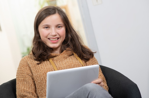 Adolescente sonriente joven que usa una tableta