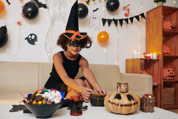 Adolescente sonriente en la mesa de decoración de sombrero de bruja cómico para la fiesta de Halloween