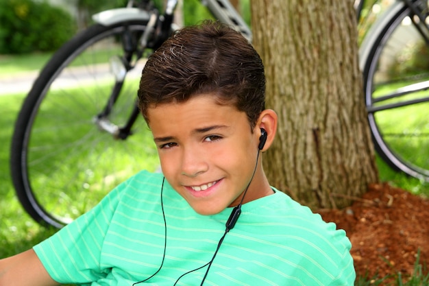 Adolescente sonriente niño escuchar música auriculares hierba