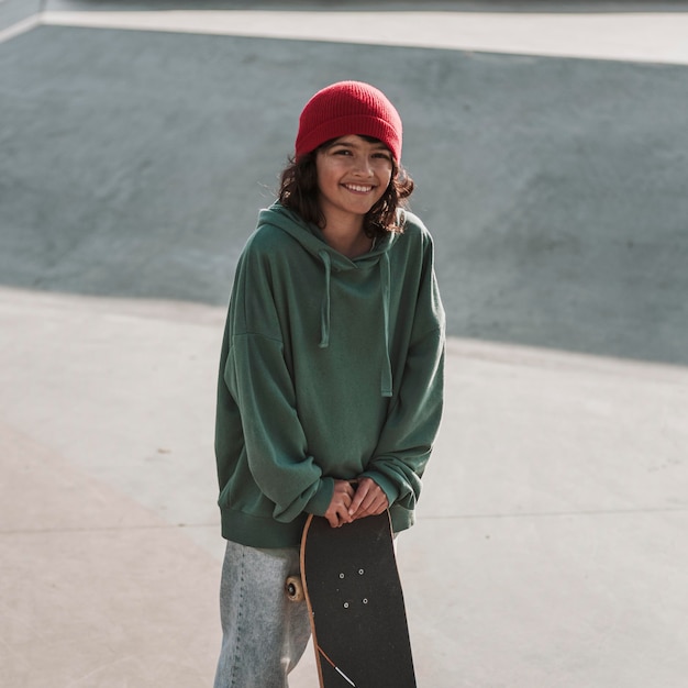 Foto adolescente sonriente con patineta en el skatepark