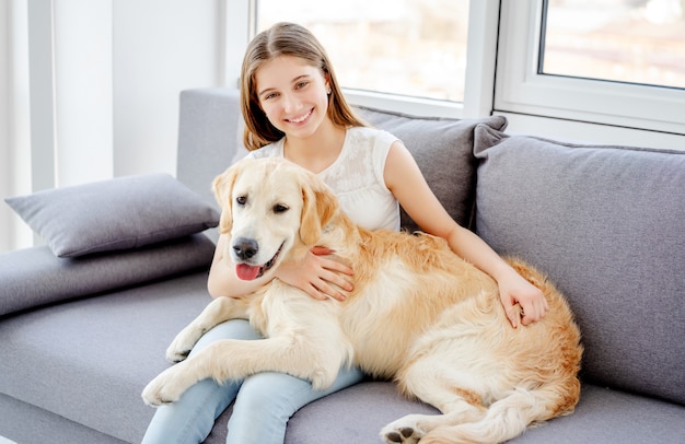 Adolescente sonriente con perro adorable en la sala de luz