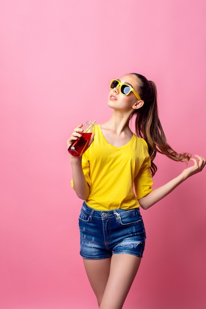 Adolescente sonriente de pie y bebiendo bebidas a través de paja