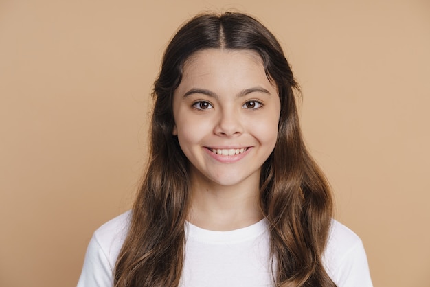 Adolescente sonriente y positiva posando sobre un fondo marrón. Encantadora chica está sonriendo dulcemente