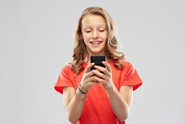 una adolescente sonriente usando un teléfono inteligente