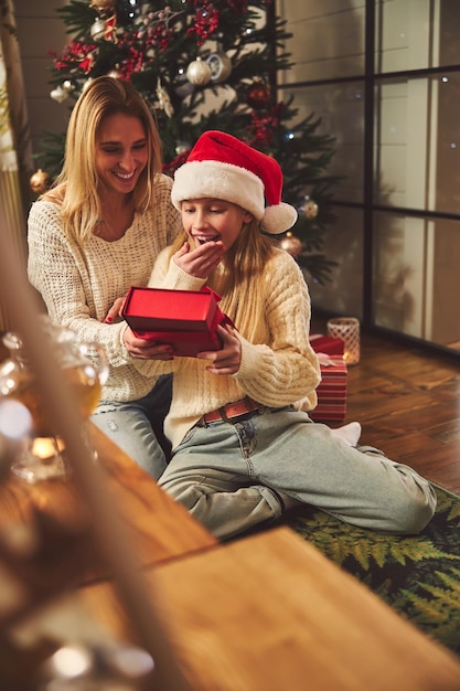 Adolescente sorprendida recibiendo regalo de mamá en Navidad