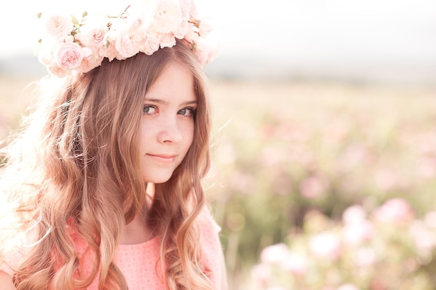 Adolescente sorridente com cabelo encaracolado e coroa de rosas ao ar livre