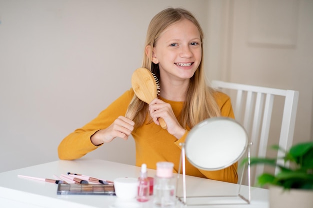 Adolescente sorridente escovando o cabelo em um ambiente interior brilhante