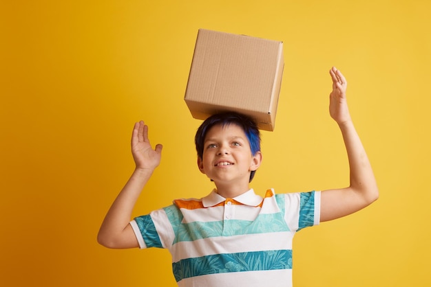 Foto adolescente sosteniendo una caja de cartón en blanco sobre un concepto de entrega de fondo amarillo aislado