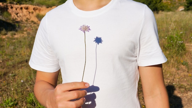 Foto adolescente sosteniendo planta púrpura salvaje cerca de sombra fuerte