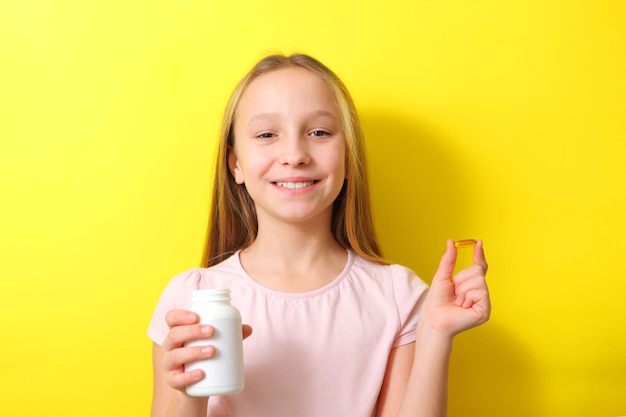 Una adolescente sostiene una cápsula omega 3 en sus manos sobre un fondo de color Suplementos naturales de aceite de pescado Foto de alta calidad