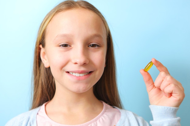 Foto una adolescente sostiene una cápsula omega en sus manos sobre un fondo de color