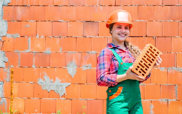 Foto una adolescente sostiene un pequeño constructor de ladrillos con un niño de ladrillos que es un ingeniero arquitecto que construye su futura casa, un niño de infancia feliz que usa casco protector para proteger la cabeza en el sitio de construcción