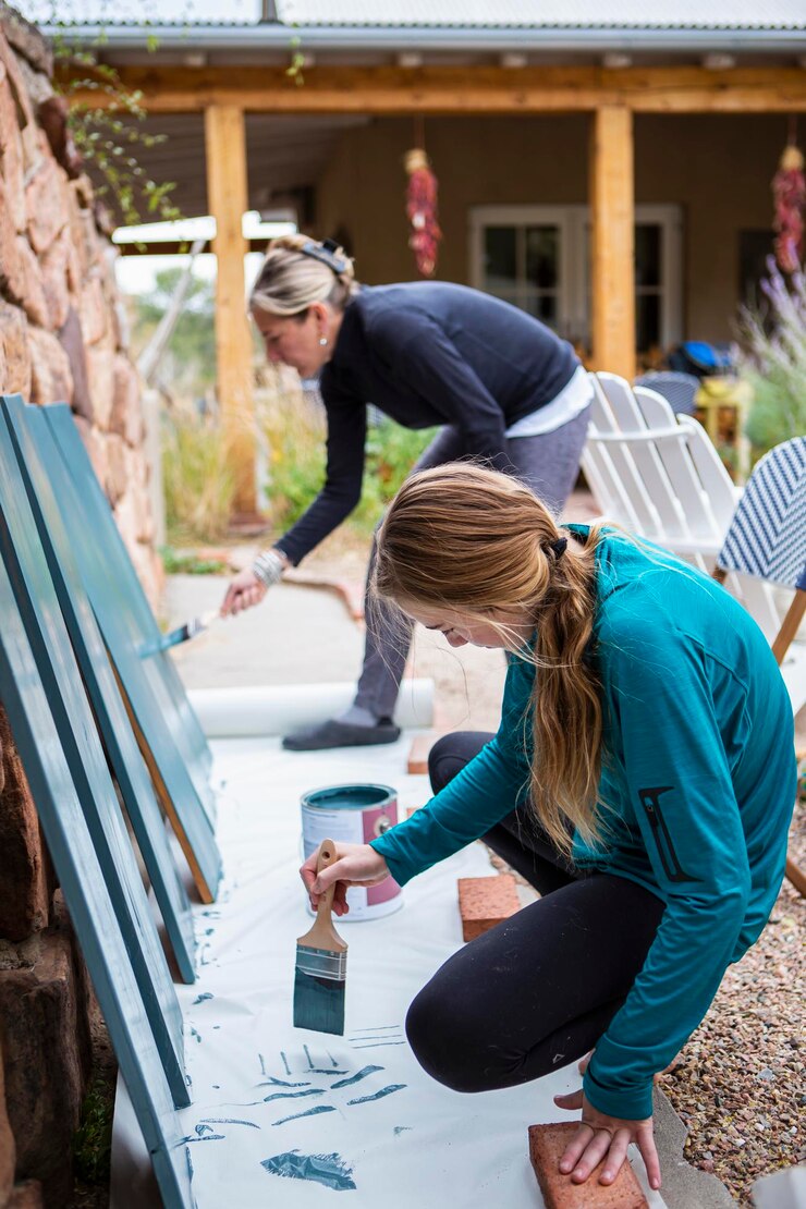 Foto adolescente y su madre pintando estantes de madera azul en una terraza
