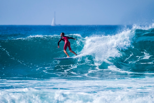 Adolescente surfando na onda em tenerife playa de las americas - wetsuits vermelhos e uma onda linda e perfeita