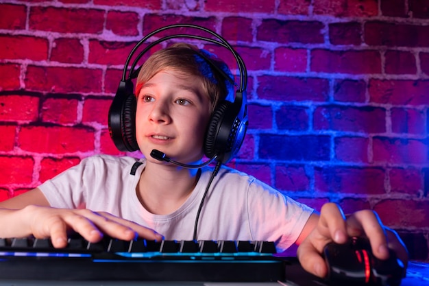 Un adolescente en un teclado con auriculares jugando videojuegos en un escritorio