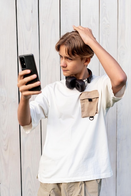 adolescente tirando uma selfie em um fundo de madeira branca ao ar livre compartilhando nas mídias sociais estilo de vida adolescente blogando adolescente auto-admiração auto-obsessão