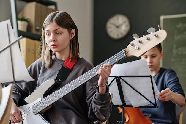 Una adolescente tocando el bajo en la escuela.