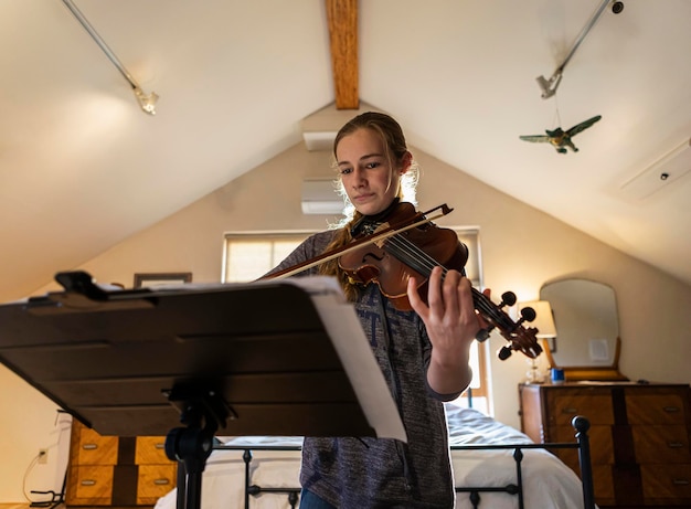 Adolescente tocando seu violino em seu quarto