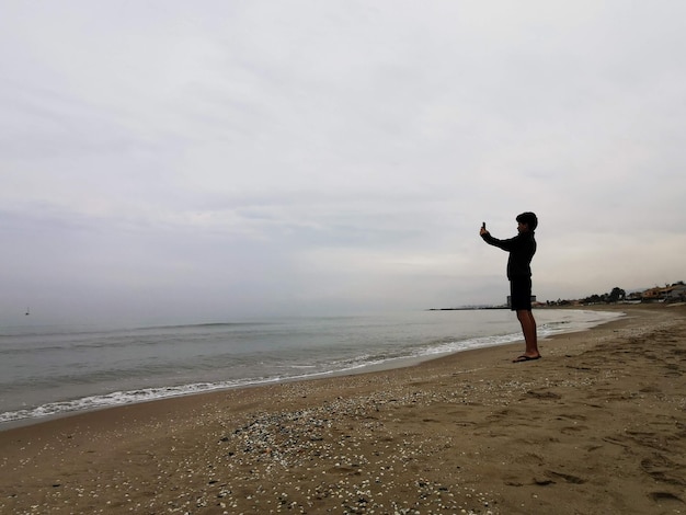 Adolescente tomando fotografías en la playa. Uso de dispositivos electrónicos