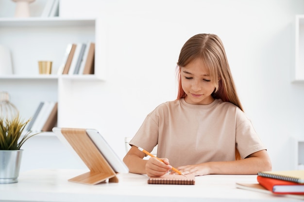 Adolescente tomando notas en el bloc de notas haciendo los deberes en la mesa en casa