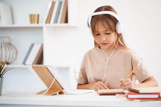 Adolescente tomando notas en el bloc de notas haciendo los deberes en la mesa en casa