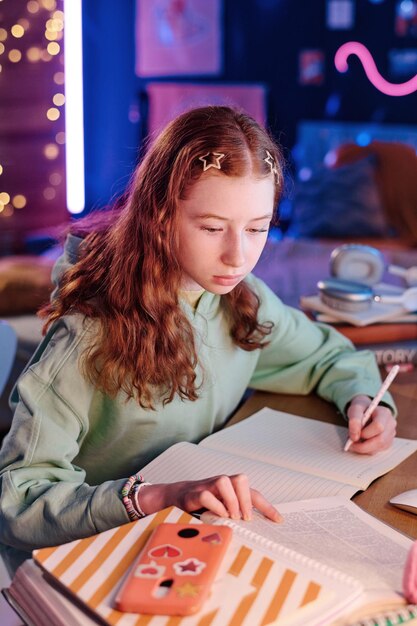 Adolescente tomando notas mientras hace la tarea