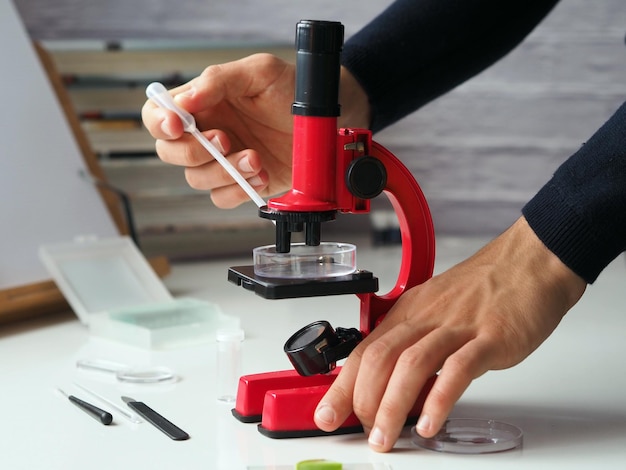 Un adolescente trabajando con una placa de Petri y un microscopio.