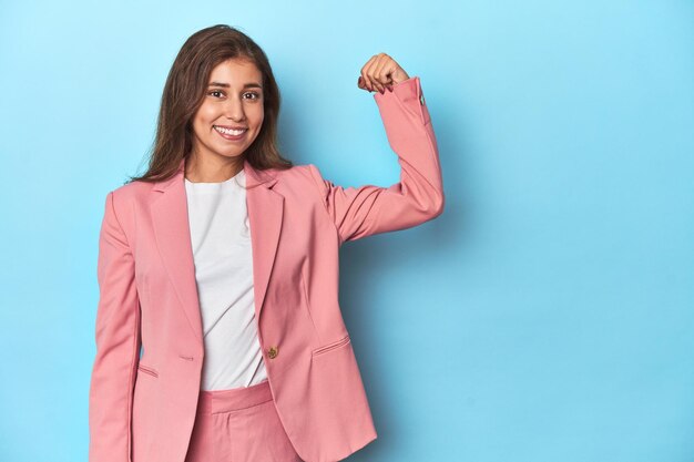Foto adolescente con traje rosa mostrando un gesto de fuerza en azul