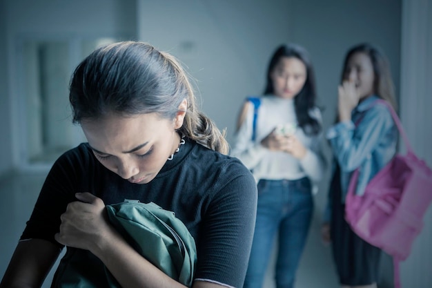 Una adolescente triste intimidada con sus amigas.