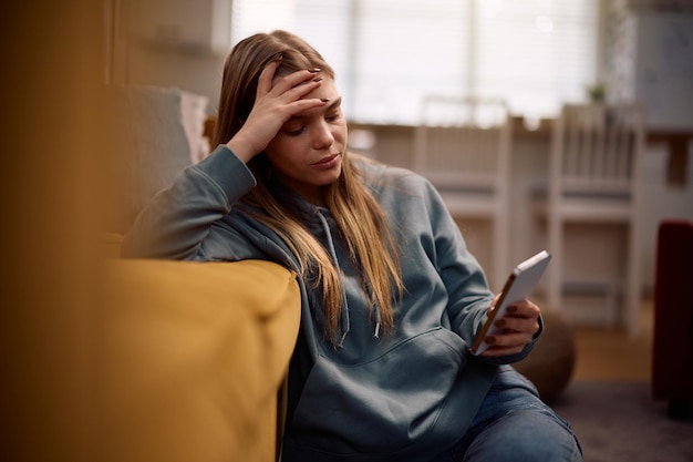 Adolescente triste lendo mensagem de texto no celular em casa