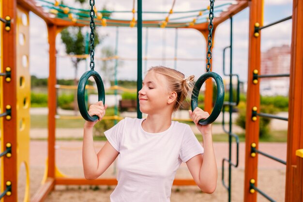 Una adolescente en uniforme deportivo practicando en el patio de recreo en un clima cálido.