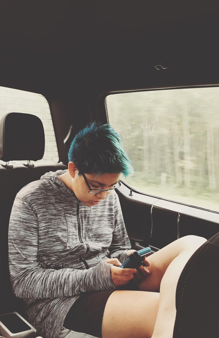 Foto adolescente usando celular enquanto está sentada no carro