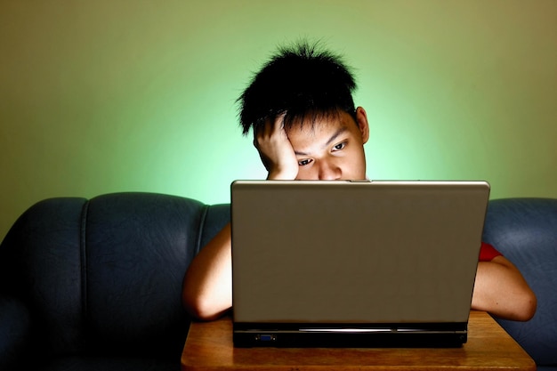 Foto adolescente usando una computadora portátil contra la pared