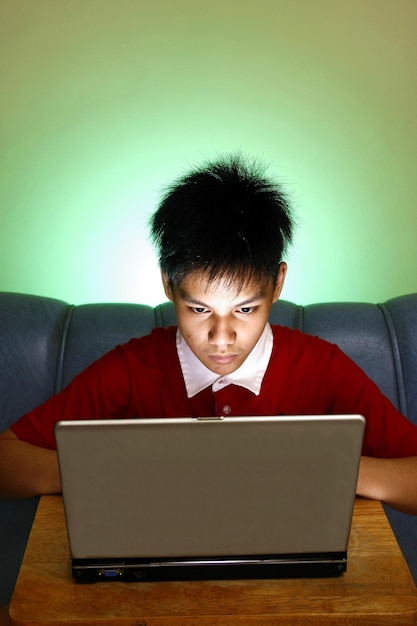 Adolescente usando una computadora portátil contra la pared