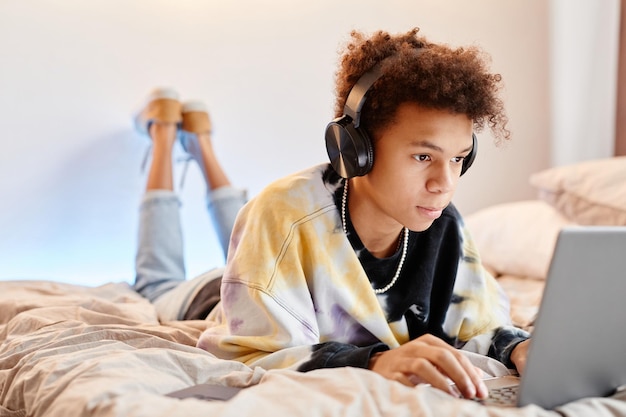 Adolescente usando laptop na cama