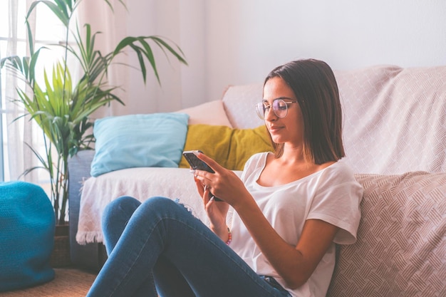 Foto adolescente usando telefone celular enquanto está sentada em casa